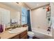 Bathroom with tan walls, wood vanity, window above the toilet, shower, and tub combo with a blue shower curtain at 6302 S Jackson Gap Ct, Aurora, CO 80016