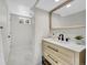 Bright bathroom with a wood vanity, a large mirror, modern fixtures, and neutral tile flooring at 10930 W Tulane Ave, Littleton, CO 80127