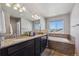 Bathroom showcasing dual sinks, granite countertops, a soaking tub, and a large vanity mirror at 2431 Nicholson St, Berthoud, CO 80513