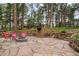 Relaxing stone patio with a fire pit and seating, surrounded by mature trees and manicured stone landscaping at 10 Long Bow Cir, Monument, CO 80132