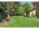 Landscaped backyard with green lawn, trees, shrubs, concrete pathway, and metal garden sculpture at 395 N Franklin St, Denver, CO 80218