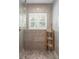 Modern shower with glass door, gray tile, pebble floor, window with white shutters, and wooden toiletries rack at 395 N Franklin St, Denver, CO 80218