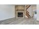 Bright living area featuring a stone fireplace, wood mantel, and modern gray floors and staircase at 11973 E Kepner Dr, Aurora, CO 80012