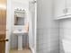 White tiled bathroom with a pedestal sink, white toilet, and shower-tub combination at 12022 W Louisiana Ave, Lakewood, CO 80228