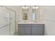 Clean bathroom with dual vanities, glass shower enclosure, and gray cabinets at 13457 Valentia St, Thornton, CO 80602