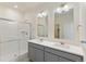 Bathroom featuring dual sinks, gray cabinetry, modern mirrors, and a glass-enclosed shower at 13457 Valentia St, Thornton, CO 80602