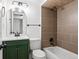 Stylish bathroom with a green vanity, arched mirror, and modern tiled shower and tub combination at 5698 E Greenwood Pl, Denver, CO 80222
