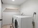 Bright laundry room featuring a pair of white laundry machines, shelf and neutral walls at 5698 E Greenwood Pl, Denver, CO 80222