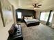 Main bedroom featuring a king bed, bench, dark accent wall, carpet, and a ceiling fan at 5285 La Quinta Cir, Elizabeth, CO 80107