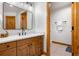 A bathroom with wood cabinets, granite countertop, framed mirror, with a tiled floor at 35 Brookhaven Ln, Littleton, CO 80123