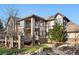 An attractive Tudor-style home featuring a deck and stone accents, complemented by mature landscaping at 35 Brookhaven Ln, Littleton, CO 80123