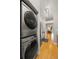 Efficient laundry area with stacked Samsung washer and dryer, and hallway leading to the open living spaces at 7452 Singing Hills Dr, Boulder, CO 80301