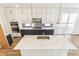 Kitchen featuring a navy blue island, white cabinets, marble countertops, stainless appliances, and herringbone backsplash at 15499 Kearney St, Brighton, CO 80602