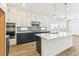 Kitchen featuring a navy blue island, white cabinets, marble countertops, stainless appliances, and herringbone backsplash at 15499 Kearney St, Brighton, CO 80602
