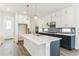 Bright kitchen featuring a navy blue island, white cabinets, marble countertops, and stainless steel appliances at 15499 Kearney St, Brighton, CO 80602