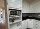 Well-lit kitchen features stainless steel microwave, white cabinets, and black countertops with gray backsplash at 10130 W 20Th Ave, Lakewood, CO 80215