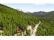 A tranquil mountain view with a quaint cabin surrounded by lush greenery and snow capped mountains in the distance at 489 Harris Dr, Idaho Springs, CO 80452
