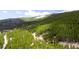 Stunning aerial shot of a hillside retreat surrounded by vast greenery and snowy mountain peaks at 489 Harris Dr, Idaho Springs, CO 80452