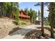 Beautiful cabin on a hillside with a driveway and a detached garage, nestled among towering trees at 489 Harris Dr, Idaho Springs, CO 80452
