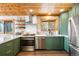 Well-lit kitchen featuring wood ceiling, stainless appliances, green cabinets, and a view from the sink window at 489 Harris Dr, Idaho Springs, CO 80452