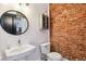 Charming bathroom featuring a vessel sink, round mirror, and exposed brick wall at 2524 Champa St # 4, Denver, CO 80205