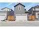The house is gray and has a white garage door and is flanked by two other houses at 23920 E 34Th Ave, Aurora, CO 80019