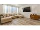 Bright living room featuring an L-shaped sofa, large windows, and a mounted television at 23920 E 34Th Ave, Aurora, CO 80019