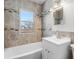 Well-lit bathroom featuring tiled walls, white vanity, and a window above the bathtub at 1570 Xanthia St, Denver, CO 80220
