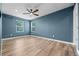 Bedroom with light wood floors, blue painted walls, ceiling fan, and natural light from two windows at 11845 W Tulane Dr, Morrison, CO 80465