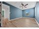 Bedroom featuring light wood floors, blue painted walls, ceiling fan, and natural light from the window at 11845 W Tulane Dr, Morrison, CO 80465