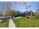 Charming blue home with a well-manicured lawn, mature trees, and a paved walkway leading to the entrance at 275 Gold Maple St, Brighton, CO 80601