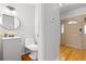 Neutral half bathroom with a round mirror, a gray vanity and hardwood floors at 6930 S Yukon Way, Littleton, CO 80128