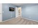 A bedroom with blue walls and carpeted floors has a TV and a doorway to another room at 6930 S Yukon Way, Littleton, CO 80128
