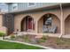 Inviting brick front porch with seating area, blossoming plants and a red front door at 6930 S Yukon Way, Littleton, CO 80128
