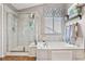 Bright bathroom featuring a glass-enclosed shower and large soaking tub beneath a window at 6950 Blue Mesa Ln, Littleton, CO 80125