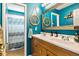 Stylish bathroom with double vanity, wood cabinets, and an ornate mirror complemented by bright blue walls at 6950 Blue Mesa Ln, Littleton, CO 80125