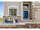 Close-up of a inviting front porch with seating area, blue accents, and brick accents at 6950 Blue Mesa Ln, Littleton, CO 80125