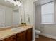 Well-lit bathroom featuring a vanity with dark wooden cabinets, a toilet, and a window with blinds at 2880 Emporia Ct, Denver, CO 80238