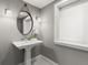 Charming powder room featuring a pedestal sink, black and white tile flooring, and elegant lighting at 2880 Emporia Ct, Denver, CO 80238
