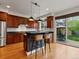 An open kitchen with dark cabinets, granite counters, an island with bar stools, and access to the outdoor patio at 2880 Emporia Ct, Denver, CO 80238