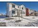 Two-story white house with gray accents, snowy yard, and other houses in the background at 2916 Oxley St, Strasburg, CO 80136
