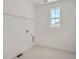 Well-lit laundry room with a window and tiled flooring, ready for appliances and storage at 2916 Oxley St, Strasburg, CO 80136