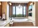 Bright bathroom featuring a soaking tub, decorative chandelier, and large window with a scenic view at 580 Summer Mist Cir, Castle Rock, CO 80104