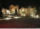 Night view of an elegant home with stone accents and professional landscaping and lighting at 580 Summer Mist Cir, Castle Rock, CO 80104