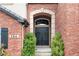 Charming front door framed by brick archway, lush greenery and decorative wreaths at 286 Claymoor Ct, Castle Pines, CO 80108