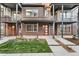 A brick and gray modern townhome featuring a covered entryway with a red front door and manicured garden at 5165 Vivian St, Wheat Ridge, CO 80033