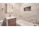 Bathroom with marble tile surround, bathtub, modern vanity, and new toilet at 8097 E Lehigh Dr, Denver, CO 80237