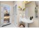 Bright bathroom with pedestal sink, glass shelves, and backyard access at 700 Holly St, Denver, CO 80220