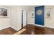 Light-filled bedroom showcasing hardwood floors, a blue accent wall, and organized closet at 700 Holly St, Denver, CO 80220