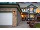 Close-up showcasing the home's brick facade, attached garage, covered entry, and neatly landscaped garden bed at 5426 S Jasper Way, Centennial, CO 80015